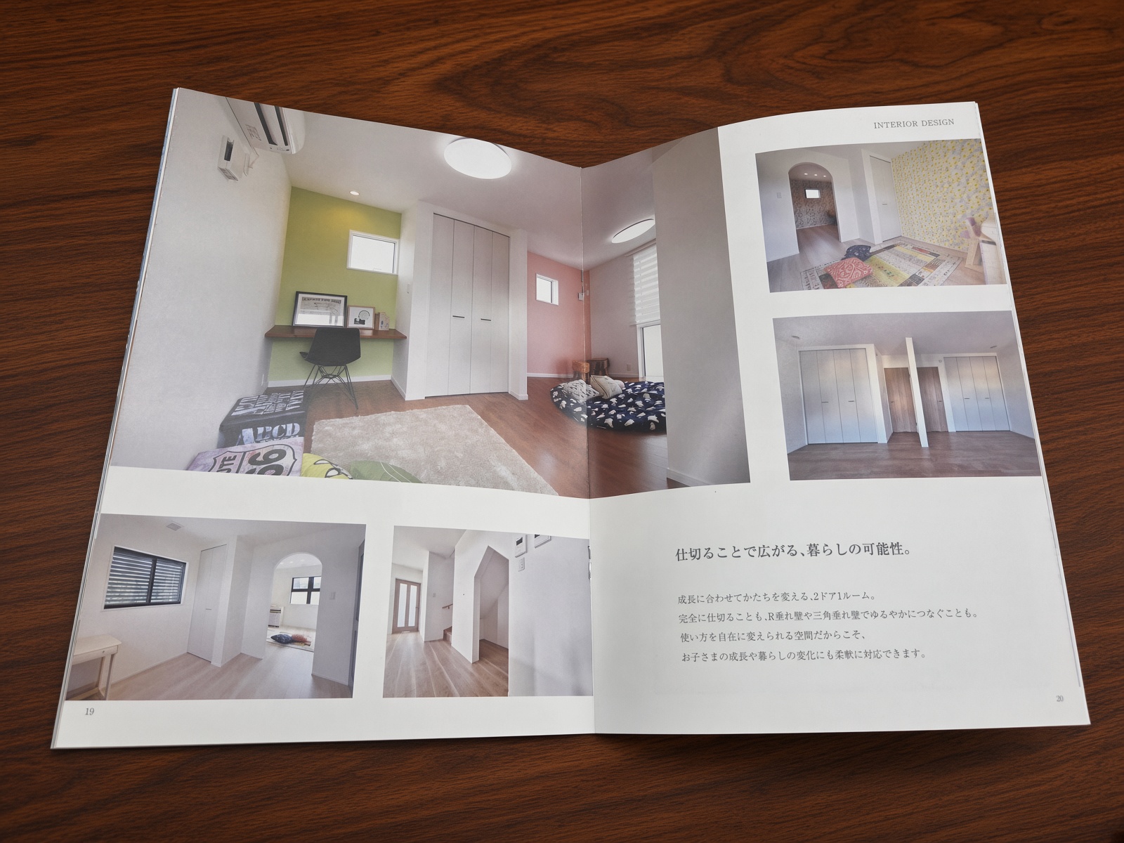 木製の机の上で開いたアローラホームのスタイルブック。室内の建築実例を紹介する見開きページ